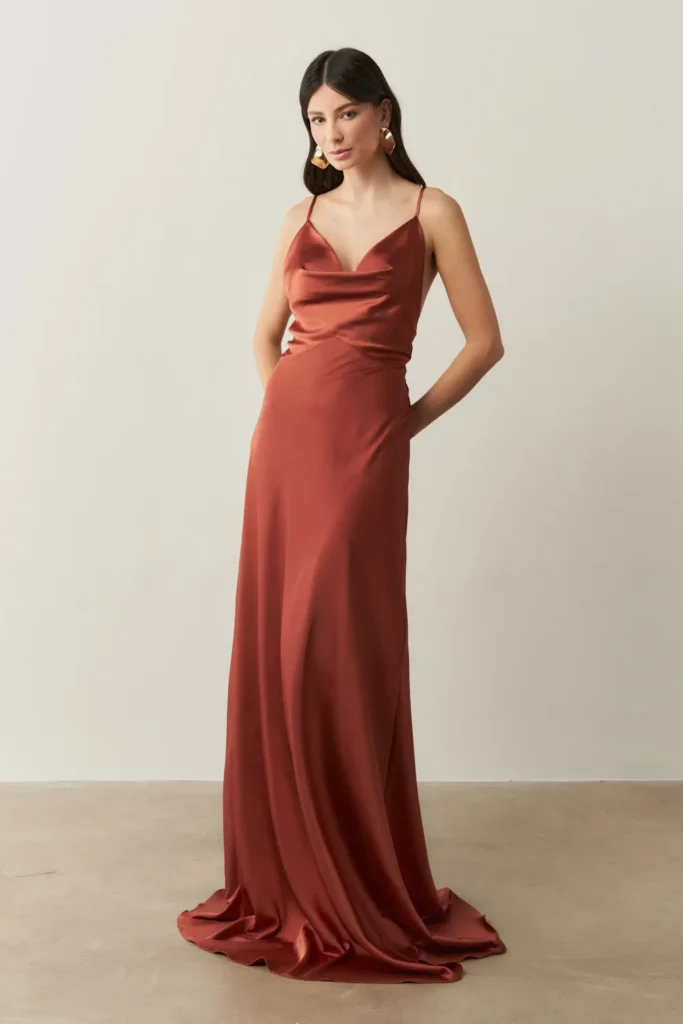 Modelo usando vestido longo de cetim fluido terracota da Koji, perfeito para eventos noturnos