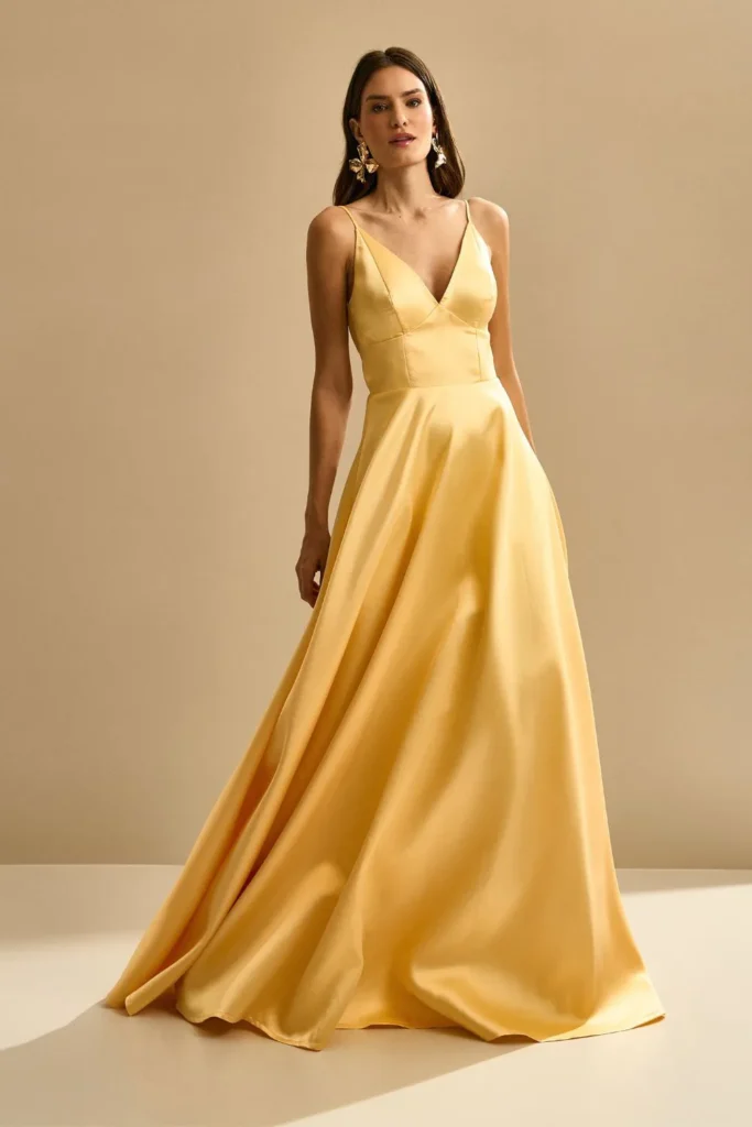 Modelo usando vestido longo amarelo fluido com alças finas da Koji, ideal para madrinhas de casamento de dia e ao ar livre