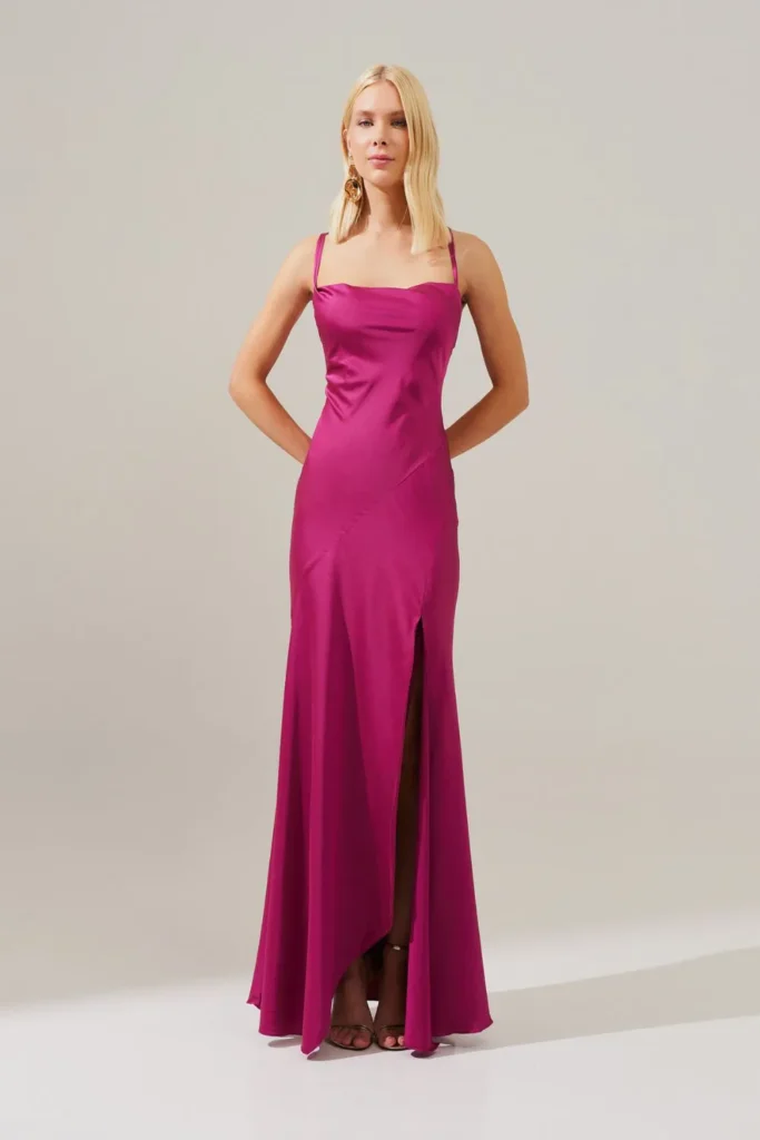 Modelo usando vestido longo fúcsia com decote degagê e costas cruzadas da Koji, ideal para convidada de festa que busca modernidade
