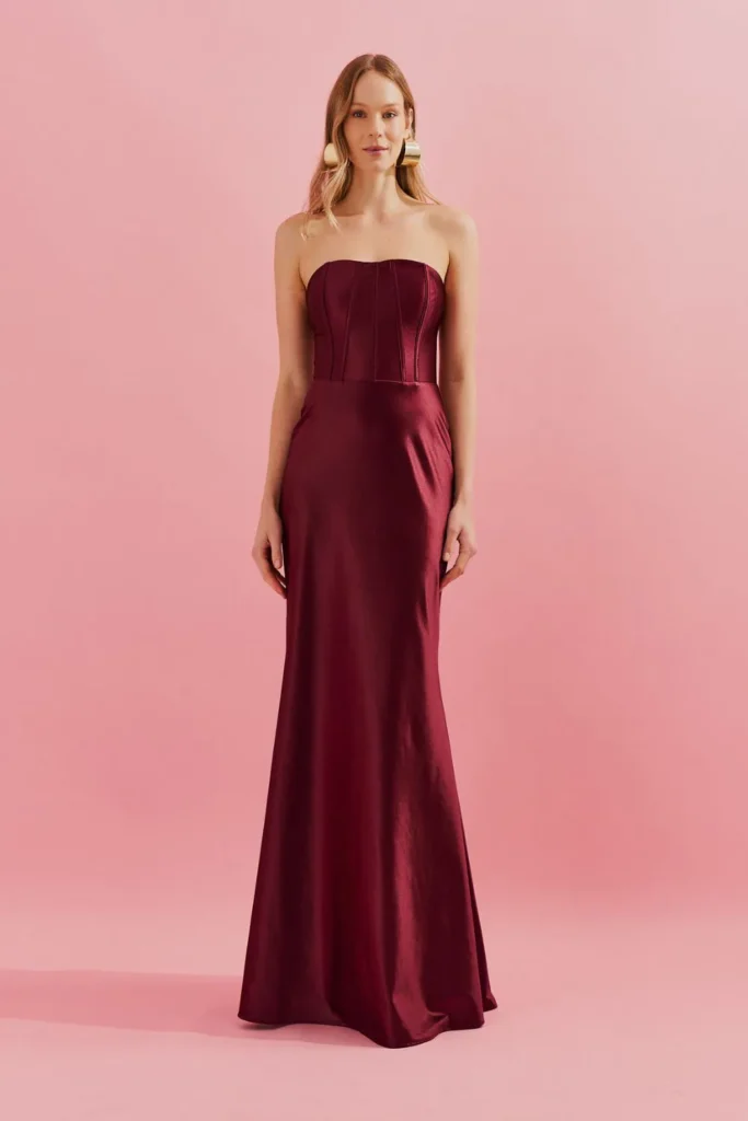 Modelo usando vestido longo marsala estruturado com decote reto da Koji, ideal para convidada elegante de festa à noite