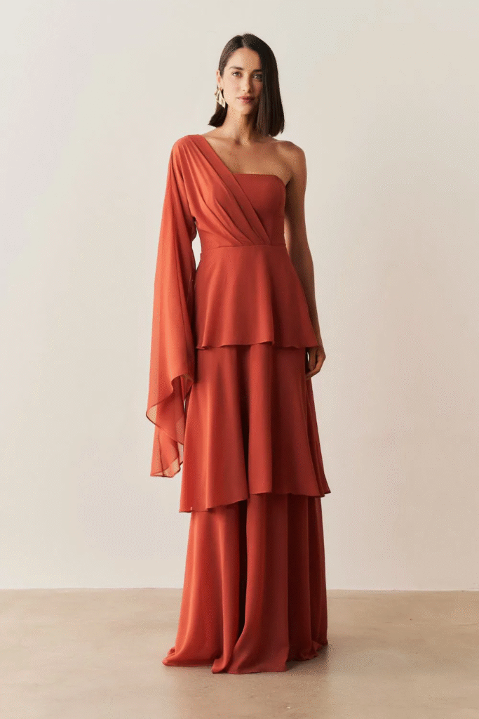 A modelo está usando o Vestido Longo com Decote Reto, Manga Longa Flare e Saia em Camadas - Austin Terracota