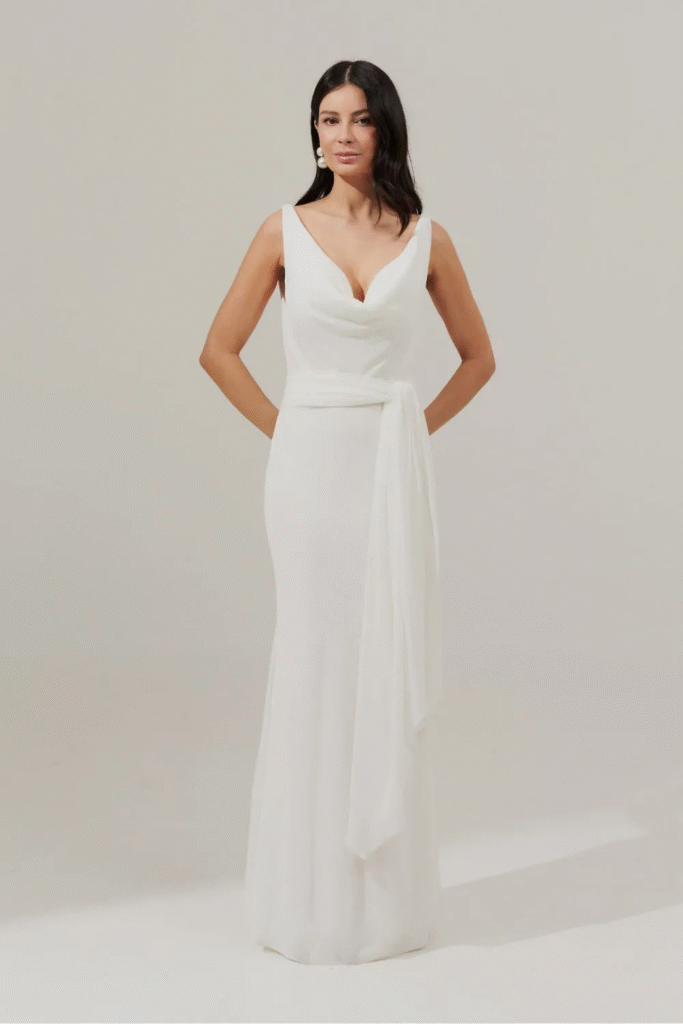 A modelo está usando o Vestido Longo com Decote Degage e Amarração na Cintura - Acapulco Off White